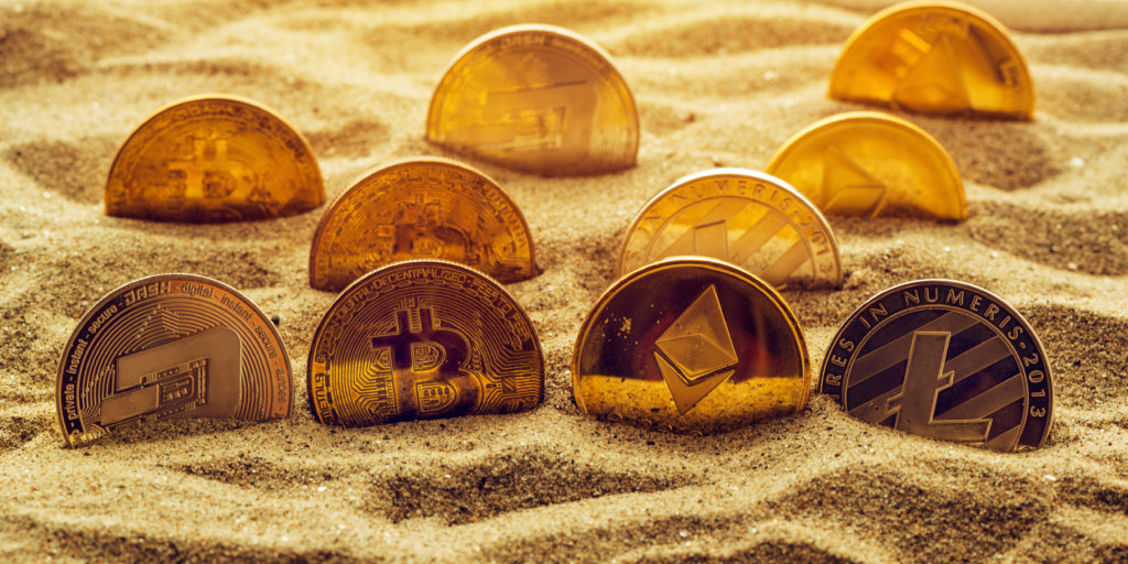 Cryptocurrency coins in sand, conceptual image for lost and found valuables that are standing the test of time.